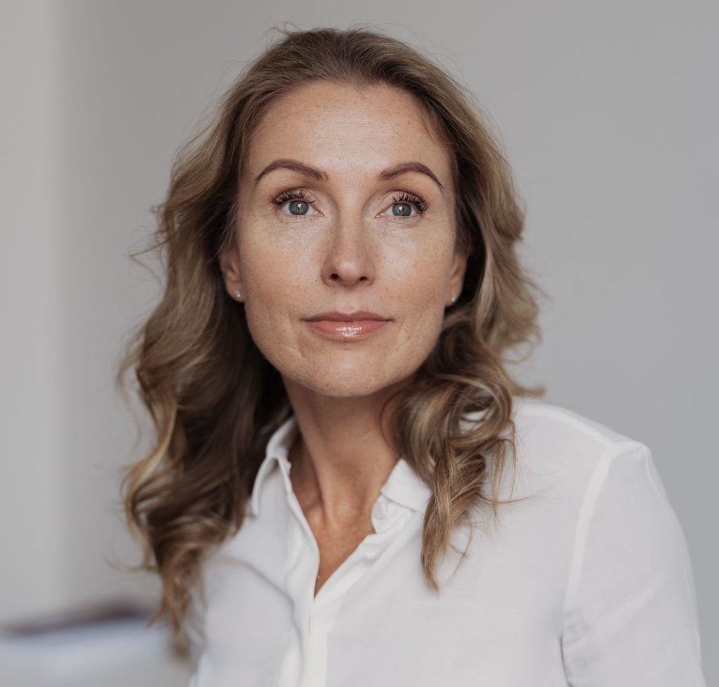 Margarita Seselgyte is a white woman in early middle age. She has long wavy fair hair and is wearing a white silk shirt