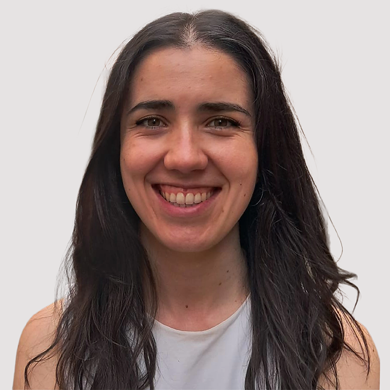 Silvia Diaz Fernandez is a young white woman with long dark straight hair. She is smiling broadly and wearing a light grey vest top